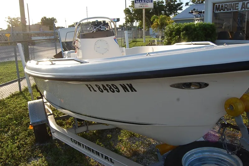 Slide: The Image of 2006 KEYWEST 152 boat on trailer, parked outdoors near a marine service shop. - 13