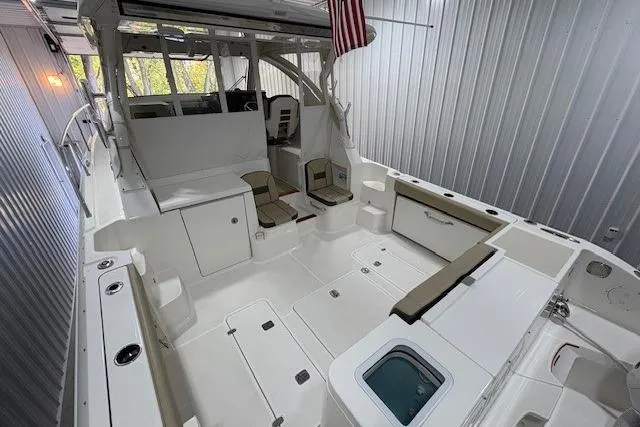 Slide: The Image of 2021 Pursuit OS 355 Offshore boat interior with seating and storage in a metal-walled space. - 10