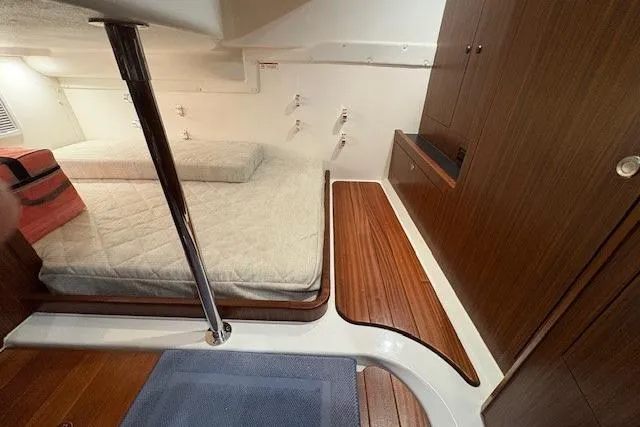 Slide: The Image of 2021 Pursuit OS 355 Offshore cabin with cushioned bed and wooden accents. - 30