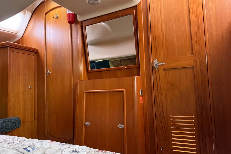 Slide: The Image of Interior of a 2004 Hunter 386 sailboat with wooden cabinetry and a mirror. - 25