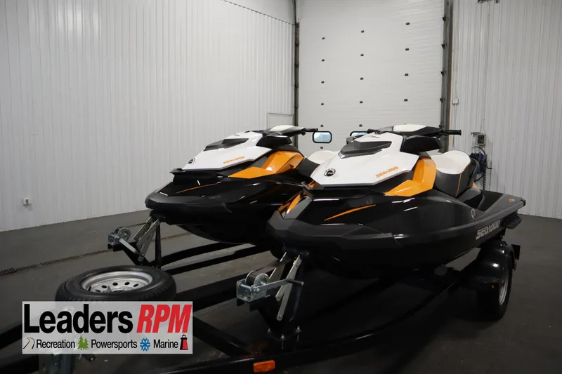 Slide: The Image of Two 2012 Sea-Doo GTR 215 jet skis on a trailer in a garage. - 1