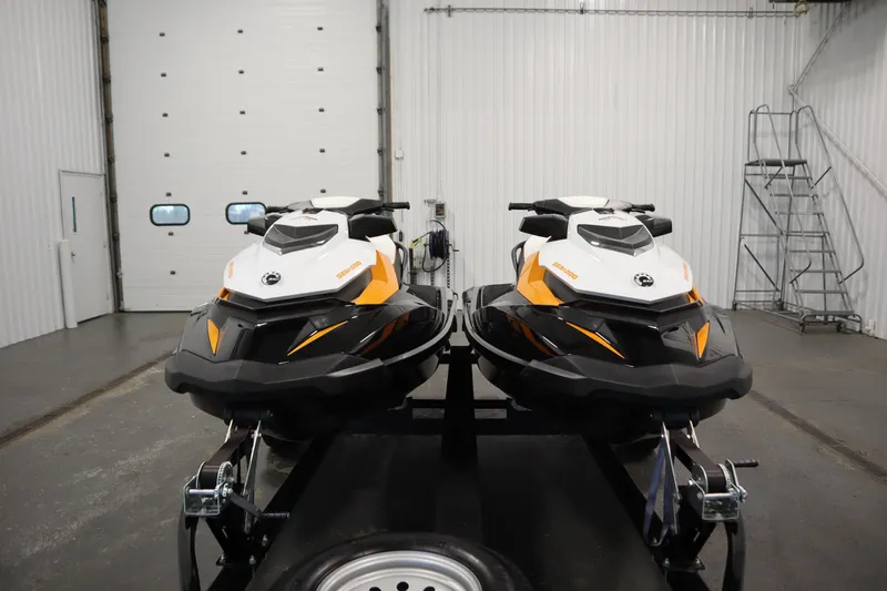 Slide: The Image of Two 2012 Sea-Doo GTR 215 jet skis on a trailer in a garage. - 2