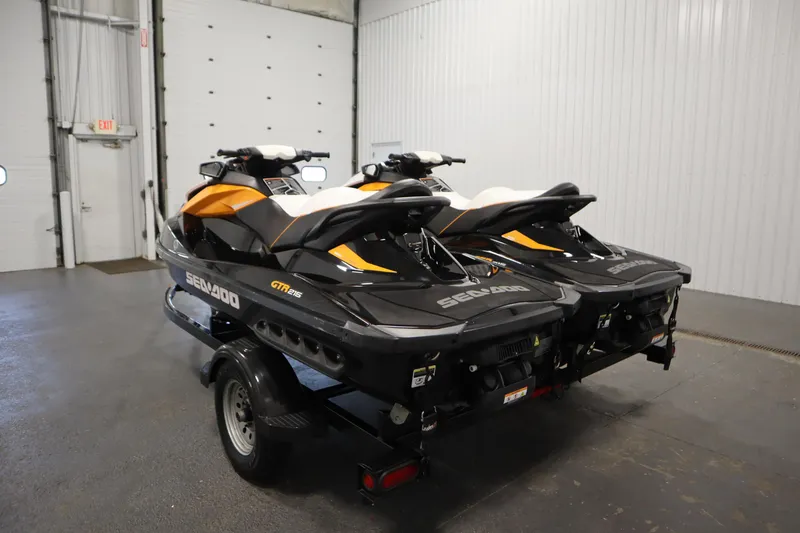 Slide: The Image of 2012 Sea-Doo GTR 215 jet skis on trailer in indoor garage setting. - 7
