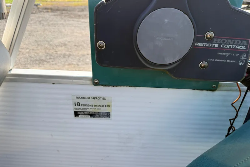 Slide: The Image of 1994 Sun Quest Sea Hunt boat with Honda remote control and capacity label for 18 people. - 13