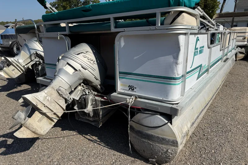 Slide: The Image of 1994 Sun Quest Sea Hunt pontoon boat with outboard motor, parked on gravel. - 3