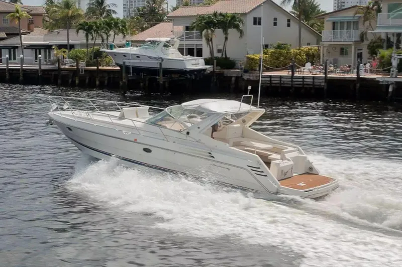 The Image of 1999 Cranchi Mediterranee 41 yacht cruising on a canal near waterfront homes. - 0