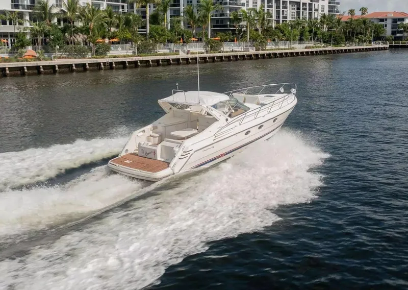 Slide: The Image of 1999 Cranchi Mediterranee 41 yacht cruising on a scenic waterway near luxury apartments. - 2