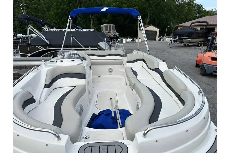 Slide: The Image of 2021 Starcraft 1915 OB Limited boat with spacious seating and blue canopy in a marina. - 13