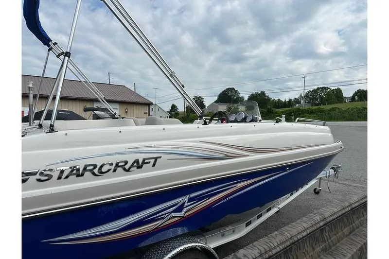 Slide: The Image of 2021 Starcraft 1915 OB Limited boat with sleek design, parked outdoors under cloudy sky. - 5