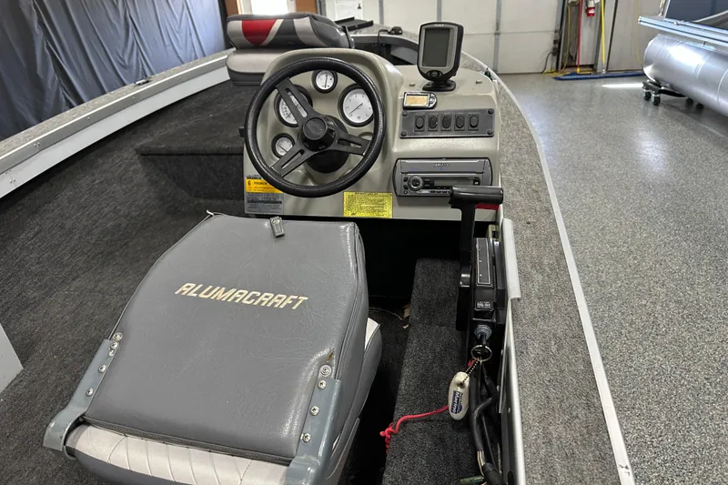 Slide: The Image of 1994 Alumacraft Classic 165 CS boat interior with carpeted flooring and storage compartment. - 13