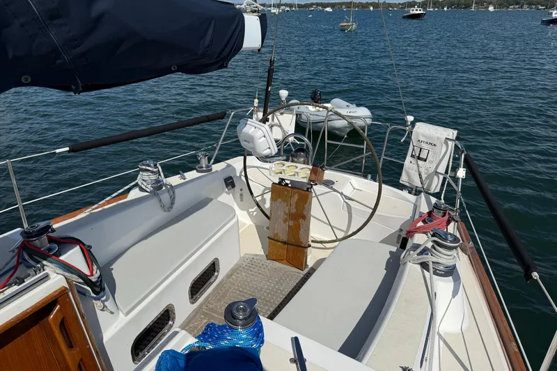 Slide: The Image of 1997 Tartan 3800 sailboat cockpit with steering wheel, moored on calm water. - 29