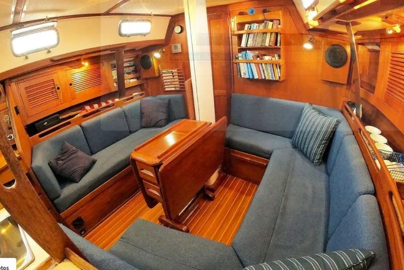 Slide: The Image of Cozy 1997 Tartan 3800 yacht interior with blue seating, wooden table, and bookshelves. - 47