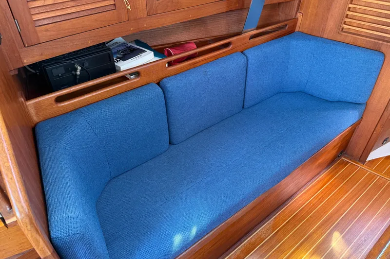 Slide: The Image of Blue cushioned seating in a 1997 Tartan 3800 sailboat interior with wooden accents. - 49