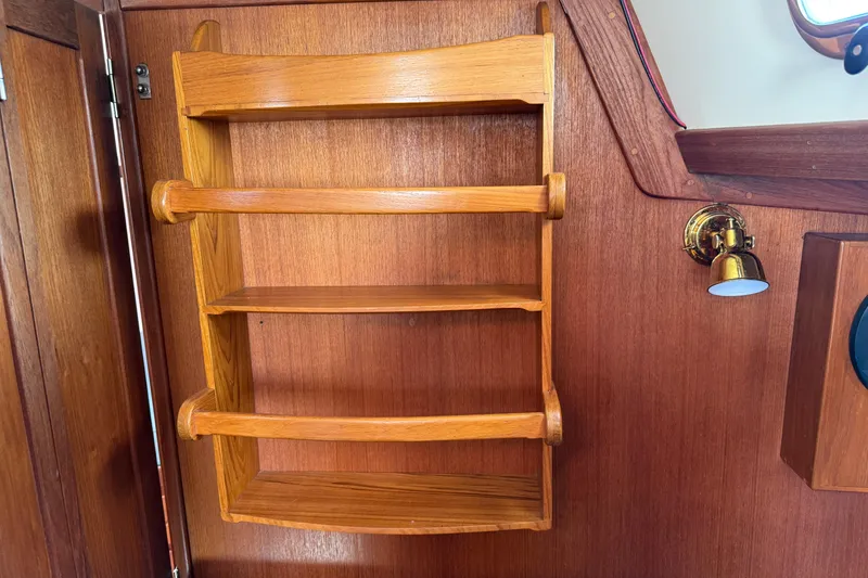 Slide: The Image of Wooden shelves inside a 1997 Tartan 3800 boat, featuring a brass wall light. - 52