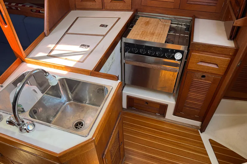 Slide: The Image of 1997 Tartan 3800 yacht kitchen with sink, stove, and wooden cabinetry. - 57