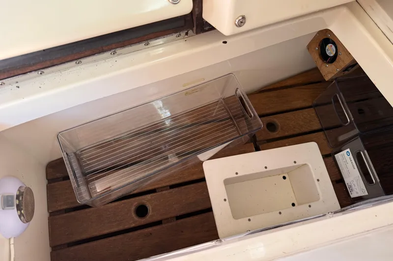Slide: The Image of Storage compartment in a 1997 Tartan 3800 boat with wooden slats and plastic containers. - 60