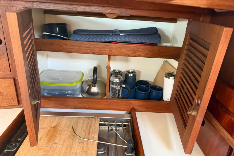Slide: The Image of Wooden kitchen cabinet in a 1997 Tartan 3800 sailboat, with mugs and kitchenware. - 65