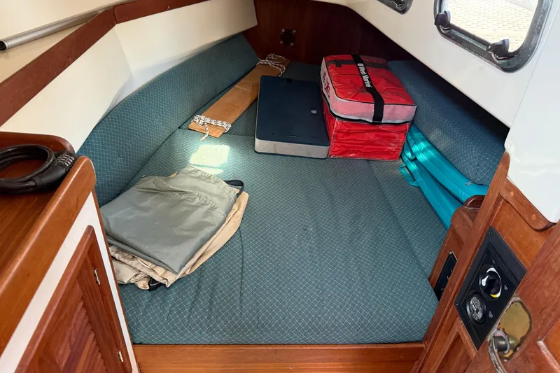 Slide: The Image of 1997 Tartan 3800 sailboat interior with cushions, storage bags, and folded clothing. - 67