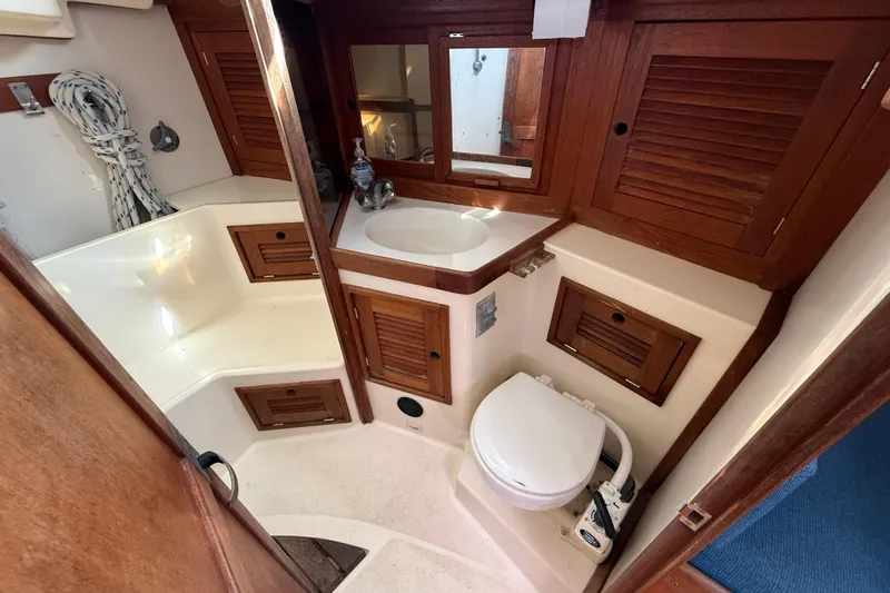 Slide: The Image of 1997 Tartan 3800 yacht bathroom with wooden cabinets, sink, and marine toilet. - 82