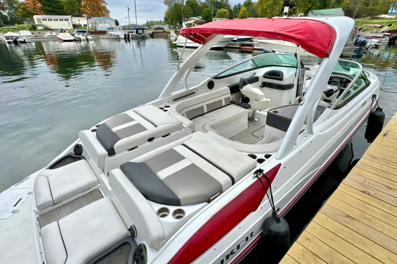 Slide: The Image of 2018 Rinker 29QX BR boat with red canopy docked at a marina. - 1