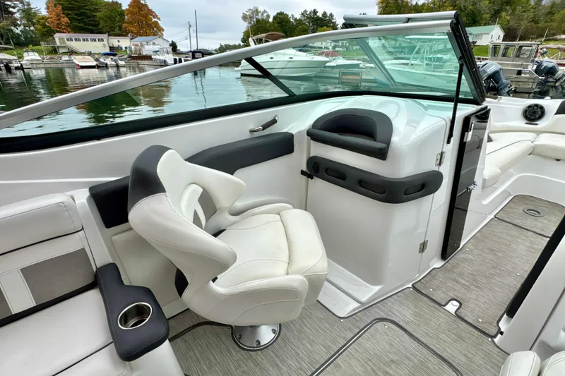 Slide: The Image of 2018 Rinker 29QX BR boat interior with white seating and sleek design at a marina. - 15