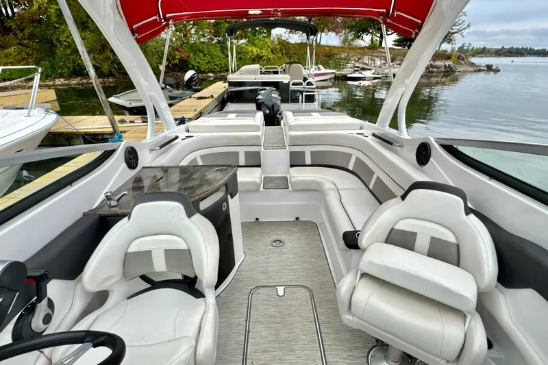 Slide: The Image of 2018 Rinker 29QX BR boat interior with white seating and red canopy. - 16
