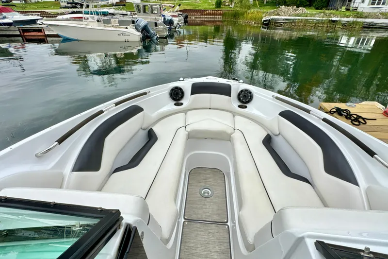 Slide: The Image of 2018 Rinker 29QX BR boat interior with cushioned seating, docked by calm water. - 18