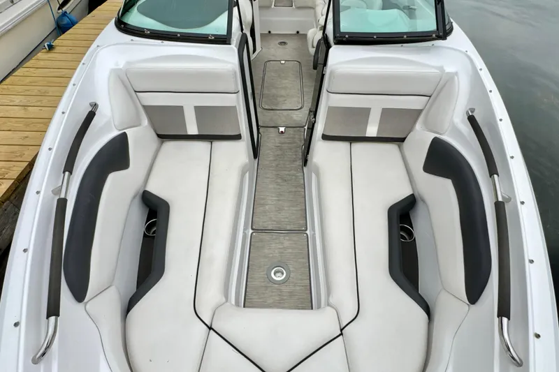 Slide: The Image of 2018 Rinker 29QX BR boat interior with white and gray seating, docked by water. - 19