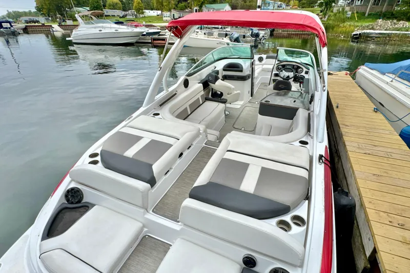 Slide: The Image of 2018 Rinker 29QX BR boat with red canopy, docked in a marina. - 2