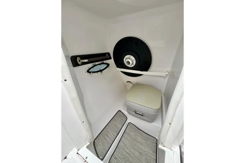 Slide: The Image of 2018 Rinker 29QX BR boat interior with compact toilet and porthole window. - 21