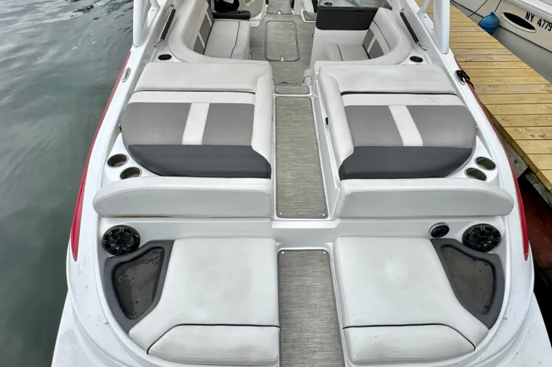Slide: The Image of 2018 Rinker 29QX BR boat interior with gray and white seating, docked by water. - 3
