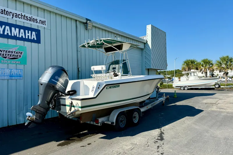 Slide: The Image of 1997 Contender 23 Open boat on trailer, parked outside dealership with Yamaha outboard motor. - 1