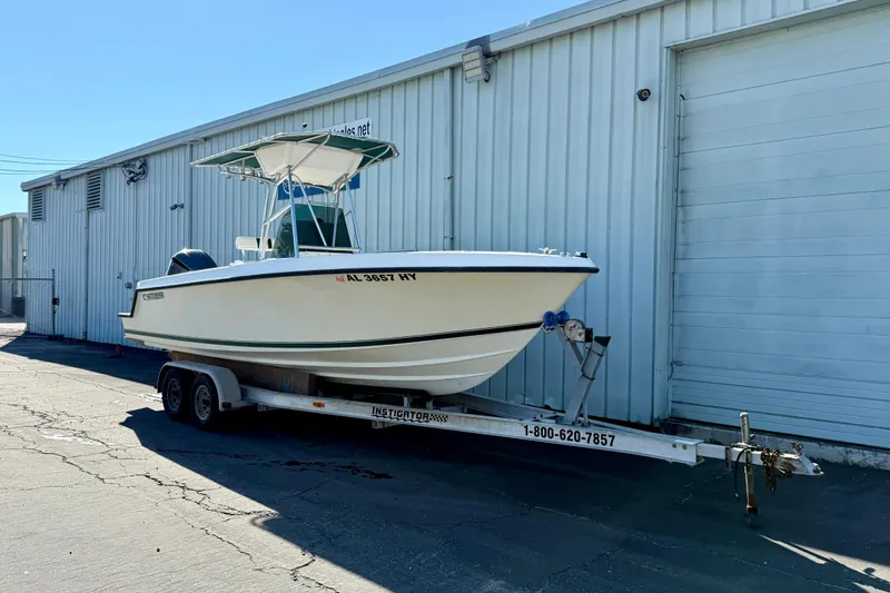 Slide: The Image of 1997 Contender 23 Open boat on trailer, parked beside a warehouse. - 2