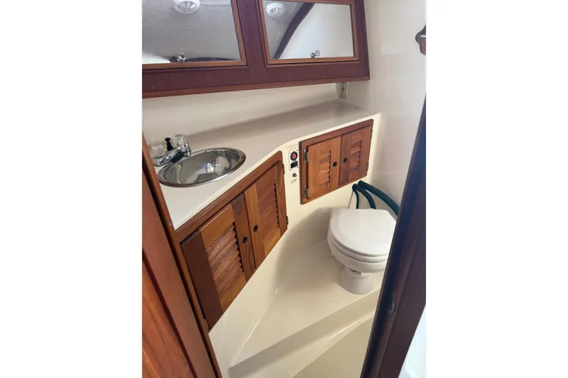 Slide: The Image of 2002 Carolina Classic 28 boat bathroom with wooden cabinets and compact sink. - 11