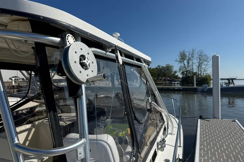 Slide: The Image of 2002 Carolina Classic 28 boat docked, featuring fishing equipment and clear blue sky. - 3