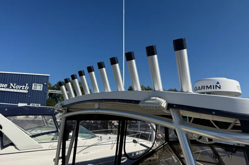 Slide: The Image of 2002 Carolina Classic 28 boat with rod holders and Garmin radar, under clear blue sky. - 4
