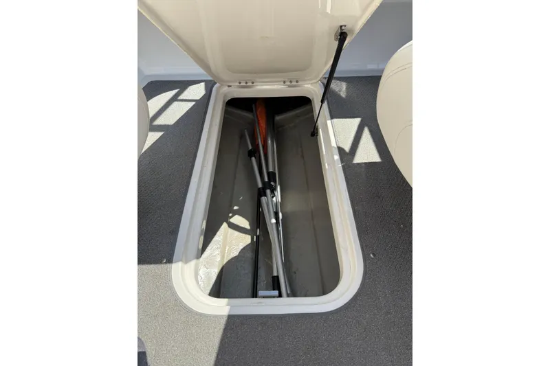 Slide: The Image of Open storage compartment in 2014 Bayliner 185 Bowrider boat, showing paddles inside. - 18