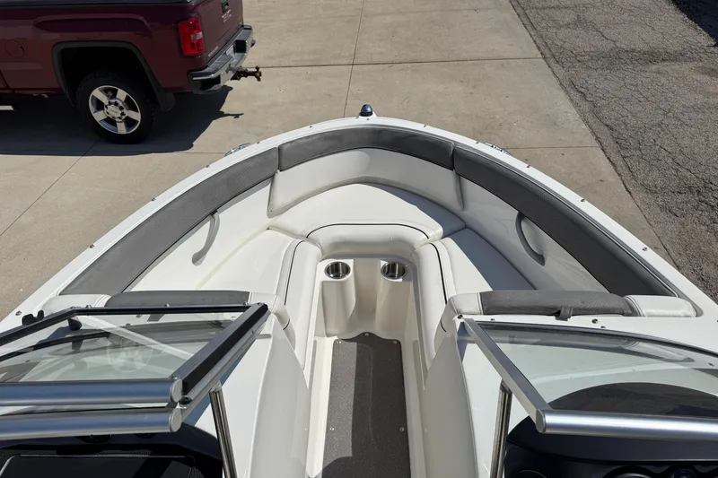 Slide: The Image of 2014 Bayliner 185 Bowrider boat interior with seating and cup holders, parked near a red truck. - 8