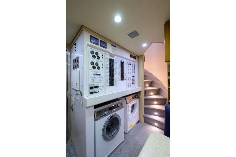 Slide: The Image of Laundry and control room inside 2001 Westport Motor Yacht Raised Pilothouse, featuring washer, dryer, and stairs. - 76
