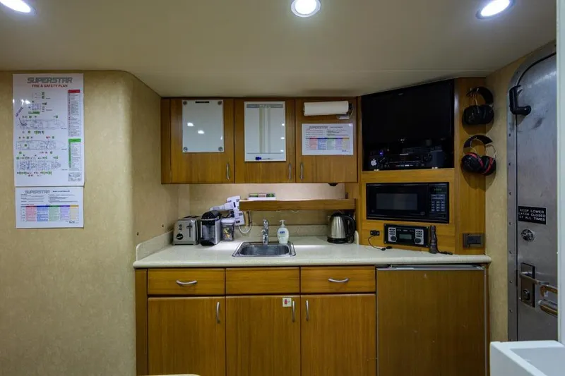 Slide: The Image of Compact kitchen area in a 2001 Westport Motor Yacht Raised Pilothouse, featuring modern appliances. - 78