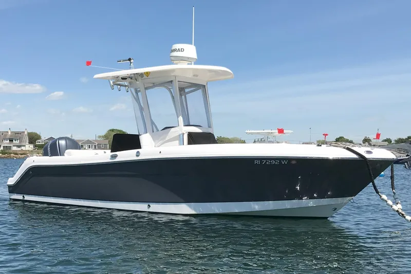 Slide: The Image of 2015 Robalo R242 Center Console boat anchored on calm water under clear blue sky. - 0