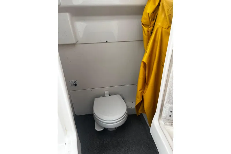 Slide: The Image of 2015 Robalo R242 Center Console boat interior with toilet and yellow raincoat. - 28