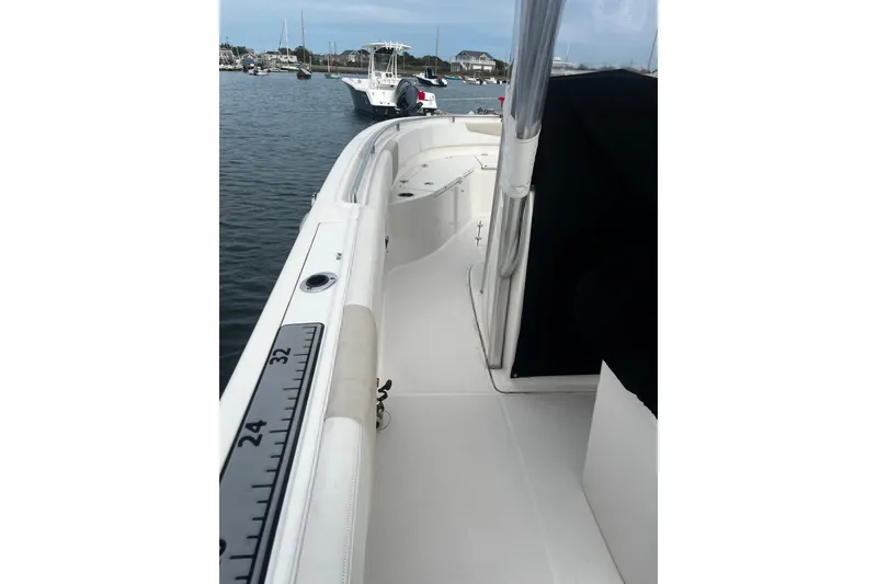 Slide: The Image of 2015 Robalo R242 Center Console boat docked in a marina, featuring spacious deck. - 49