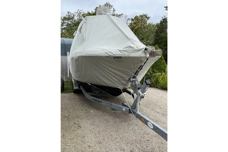 Slide: The Image of 2015 Robalo R242 Center Console boat covered on a trailer in a driveway. - 57