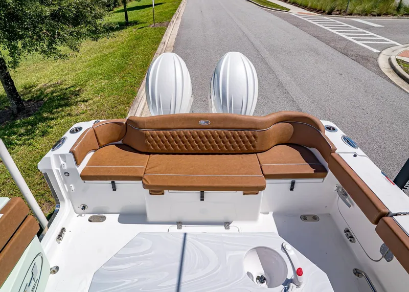 Slide: The Image of 2026 Sea Hunt Ultra 275 SE boat with brown seating and dual engines, parked on a road. - 7