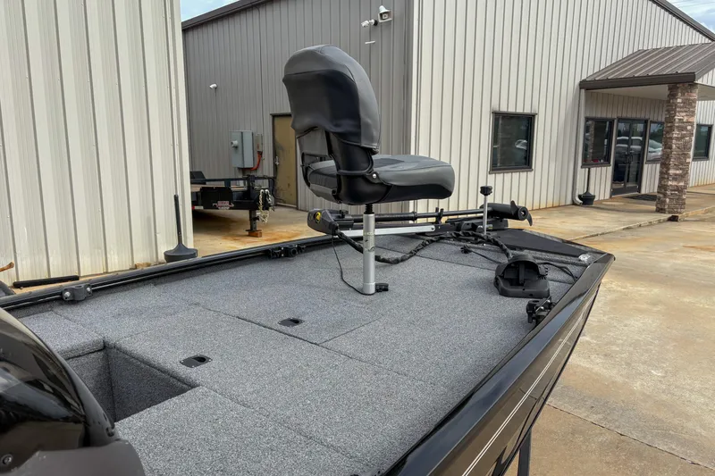 Slide: The Image of 2023 Tracker Pro 170 boat with a swivel seat, parked near a metal building. - 3