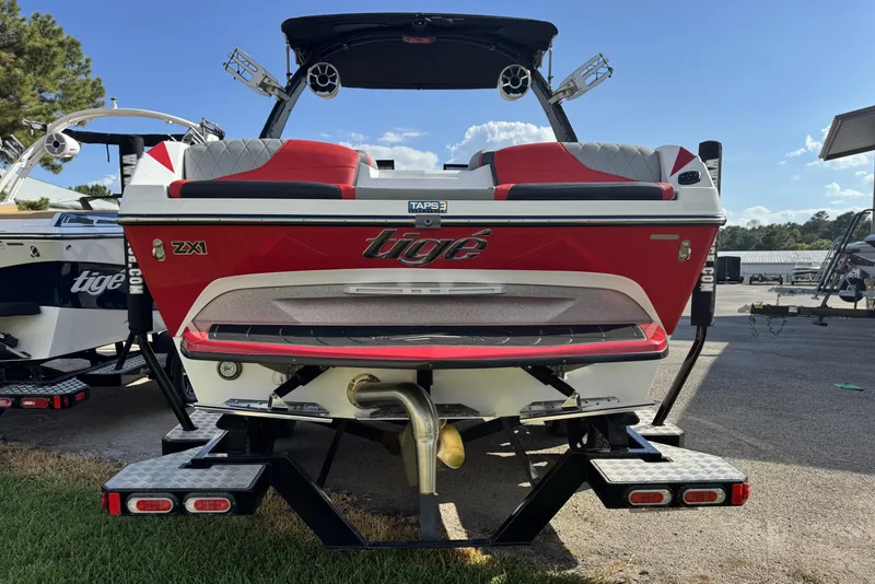 Slide: The Image of 2019 Tigé ZX1 boat, red and white, parked on a trailer in a sunny outdoor setting. - 3