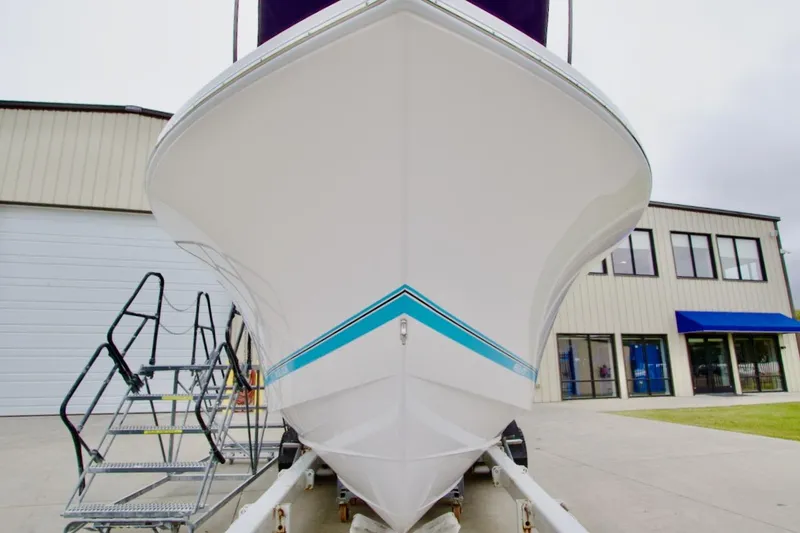 Slide: The Image of 2026 Regulator 25 boat on trailer, front view, near industrial building. - 1
