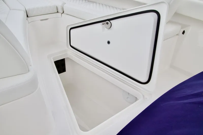 Slide: The Image of 2026 Regulator 25 boat storage compartment with white interior and secure latch. - 12