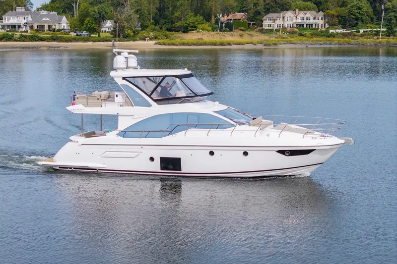 Slide: The Image of 2020 Azimut Fly 50 yacht cruising on a serene lake with luxury homes in the background. - 1